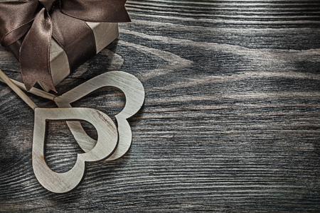 Gift box with tied bow white wooden hearts on vintage wood board celebrations concept.の写真素材