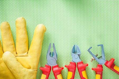 Composition of leather protective gloves insulation strippers nippers pliers on green background electricity concept.の写真素材