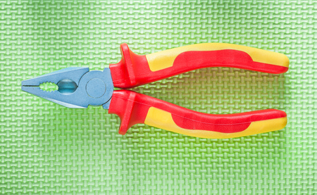 Insulation pliers on green surface electricity concept.の写真素材
