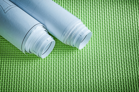 Rolled engineering drawings on green background construction concept.
