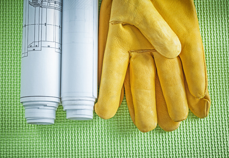 Protective leather gloves rolled blueprints on green background construction concept.の写真素材