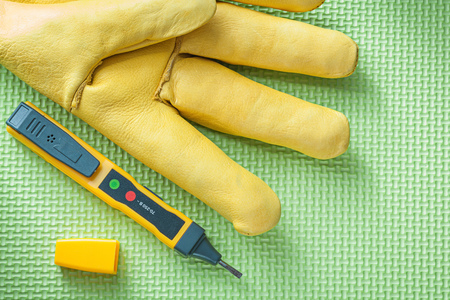 Leather safety glove electrical tester on green background electricity concept.