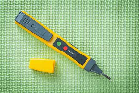 Electrical tester detector on green background electricity concept.