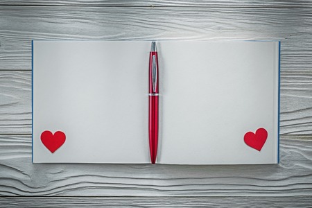 Red hearts ball-point pen clean notebook on wood board education concept.の写真素材