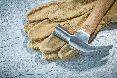 Leather safety gloves claw hammer on metallic background construction concept.