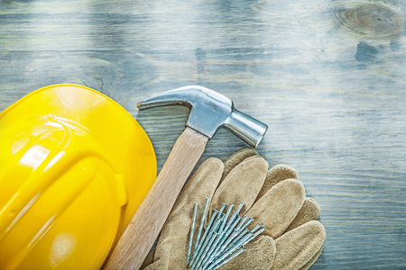Leather protective gloves claw hammer nails hard hat on wooden board construction concept.