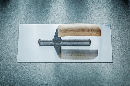 Stainless bricklaying trowel on concrete background construction concept.