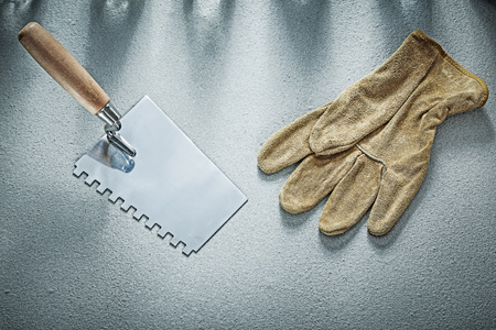 Bricklaying trowel leather safety gloves on concrete background construction concept.の写真素材