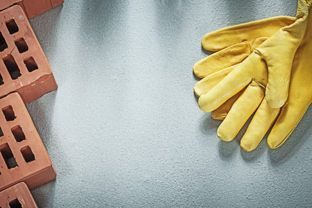 Composition of orange construction bricks leather protective gloves on concrete background building...