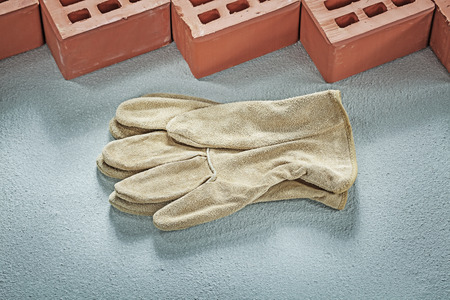 Orange bricks leather safety gloves on concrete surface building concept.