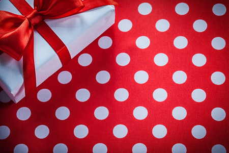 White gift box with tied ribbon on polka-dot red fabric celebrations concept.の写真素材