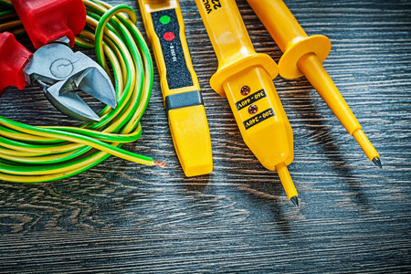 Electric tester nippers rolled wire on wooden board.