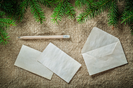 Fir tree twig envelope paper pencil on bagging background.