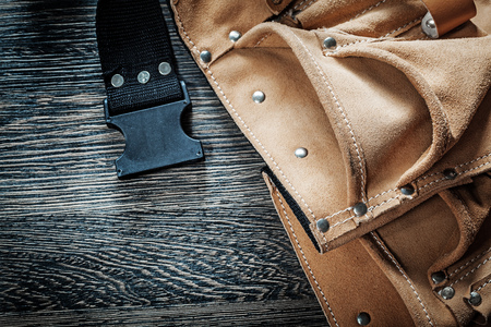 Leather toolbelt on black wooden board.の写真素材