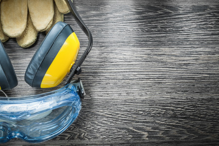 Protective spectacles, gloves and earmuffs on wooden board.の写真素材