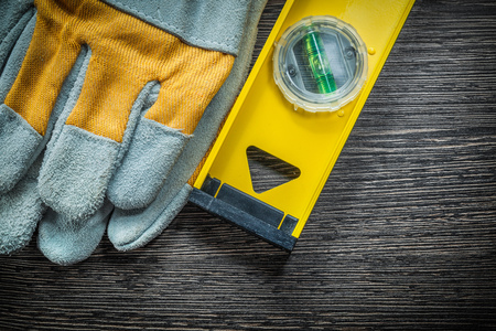 Yellow construction level working gloves on wooden board.
