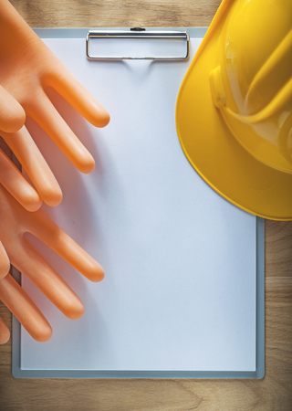 Clipboard paper building helmet insulating gloves on wooden board.の写真素材