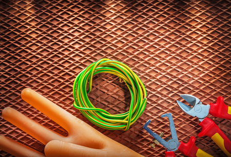 Insulation wire strippers cutter electric cable electricians gloves on dielectric mat.