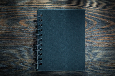 Black spiral notebook on vintage wooden board.の写真素材