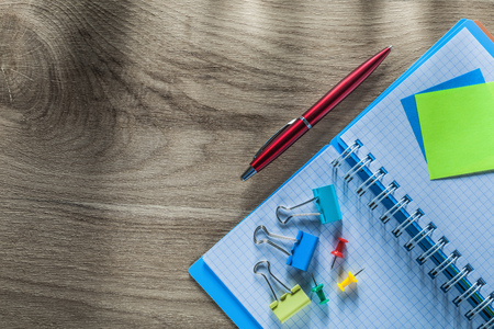 Reminder notes notebook pen drawing pins paper clips on wooden board.