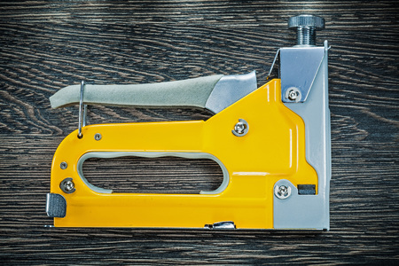 Building stapler gun on wooden board.