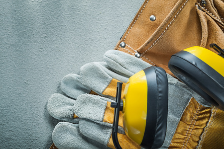 Leather tool belt protective gloves earmuffs on concrete background.の写真素材