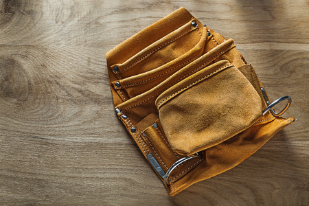 Leather toolbelt on wooden board.