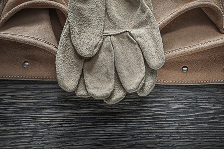 Tool belt safety gloves on wooden board.
