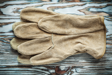 Leather protective gloves on wooden board.