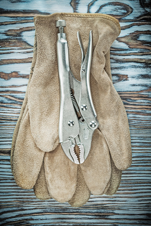 Leather safety gloves lock jaw pliers on wooden board.の写真素材