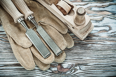 Safety gloves flat chisels planer on wooden board.