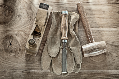 Lump hammer shaving plane chisel safety gloves on wooden board.の写真素材
