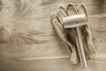 Safety gloves lump hammer on wooden board.