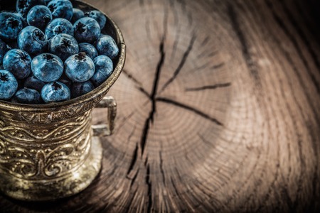 Ripe huckleberries in vintage metal bowl on grunge board.の写真素材