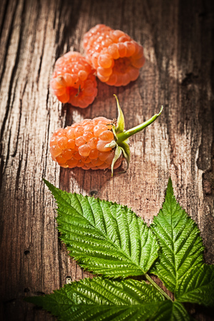 Red blackberries leaf on vintage wooden board.