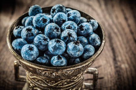 Blueberries in vintage metal bowl on grunge board.の写真素材