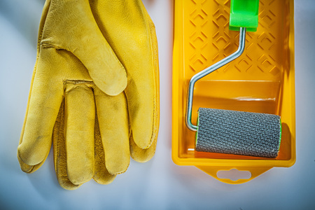 Leather protective gloves paint tray roller on white background.