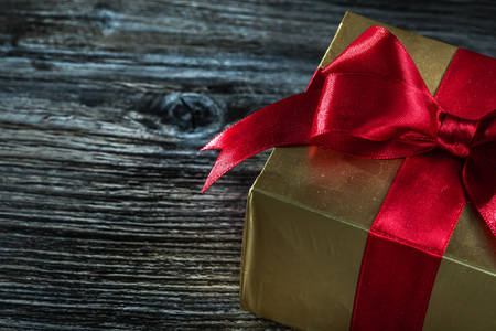 Golden gift box with bow on wooden board.の写真素材