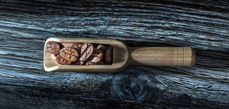 Roasted coffee grains in scoop on wooden board.の写真素材