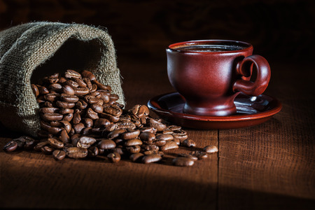 coffee cup and sack with beans on wood board