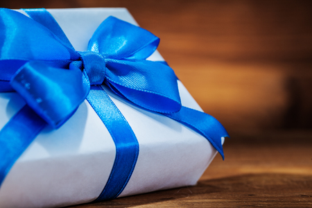 very close up white giftbox with blue ribbon on vintage woodの写真素材