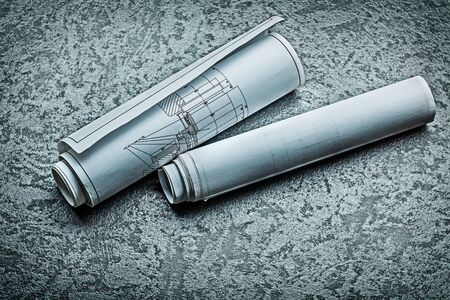 two rooled up blueprints on black background