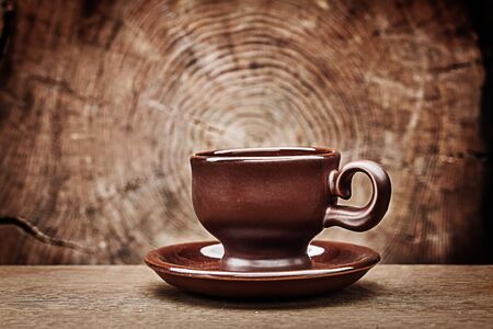 single brown coffee cup on vintage wood background with cross cut of tree trunkの写真素材