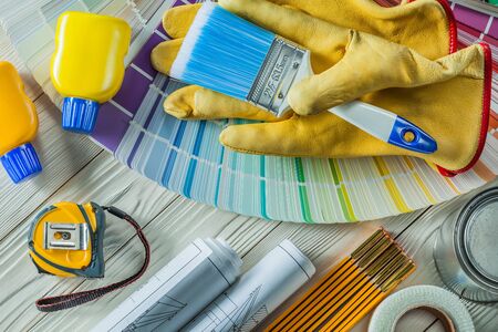 paint brush in working gloves with any other construction tools on white wood boards