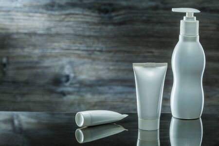 tubes and sprayer skincare items on dark background