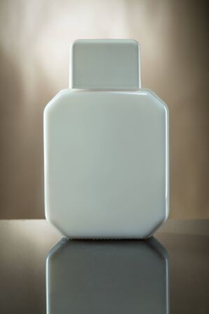 blank plastic white bottle for cosmetic or toiletry product on brown backgroundの写真素材