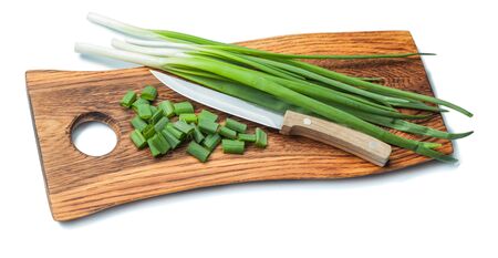 green chopped scallions and kitchen knife on vintage wooden chopping board with life eddge isolatedの写真素材