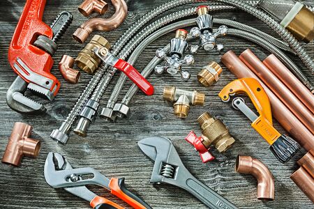 plumbing concept big set of piping accessories monkey and plumb adjustable wrenches copper brass fittings pipe cutter on vintage wood backgroundの写真素材