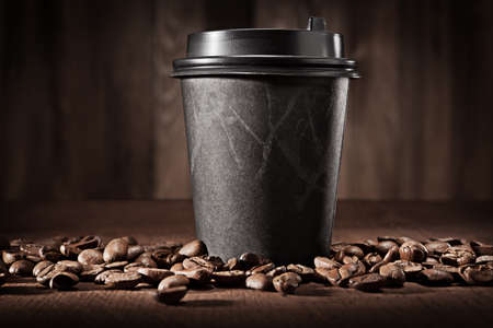 Hot Fresh Brewed Flavored Coffee. Classic Black Paper Cup. On Vintage Wooden Background With Coffee Beans.の写真素材