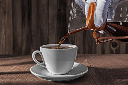 Hand Weared In White Glove Pours Fresh Brewed Tasty Coffee From Coffee Dripper Into Ceramic Cup